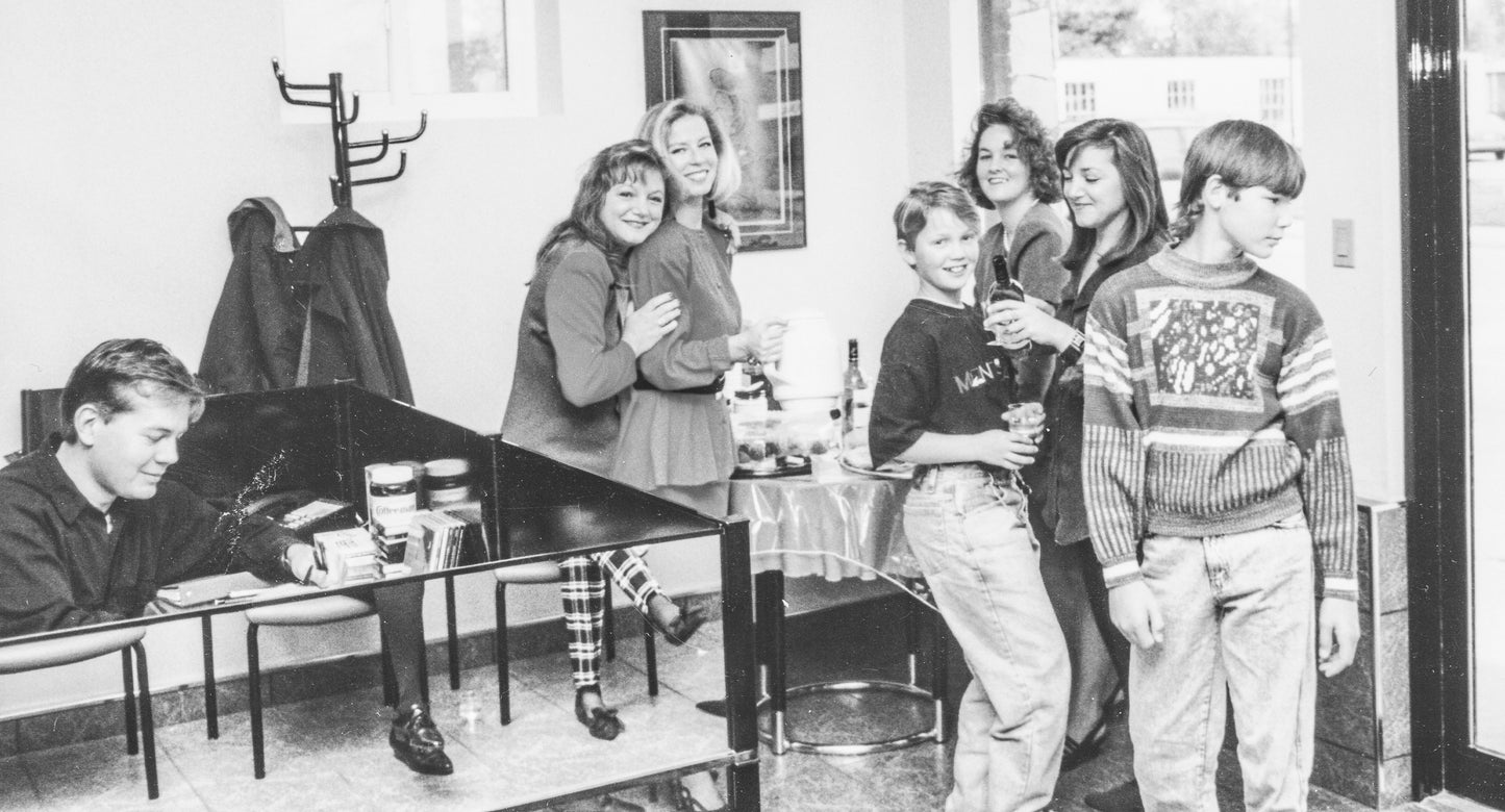 black and white photo of Lina's staff at her salon, and her son, posing at a staff celebration