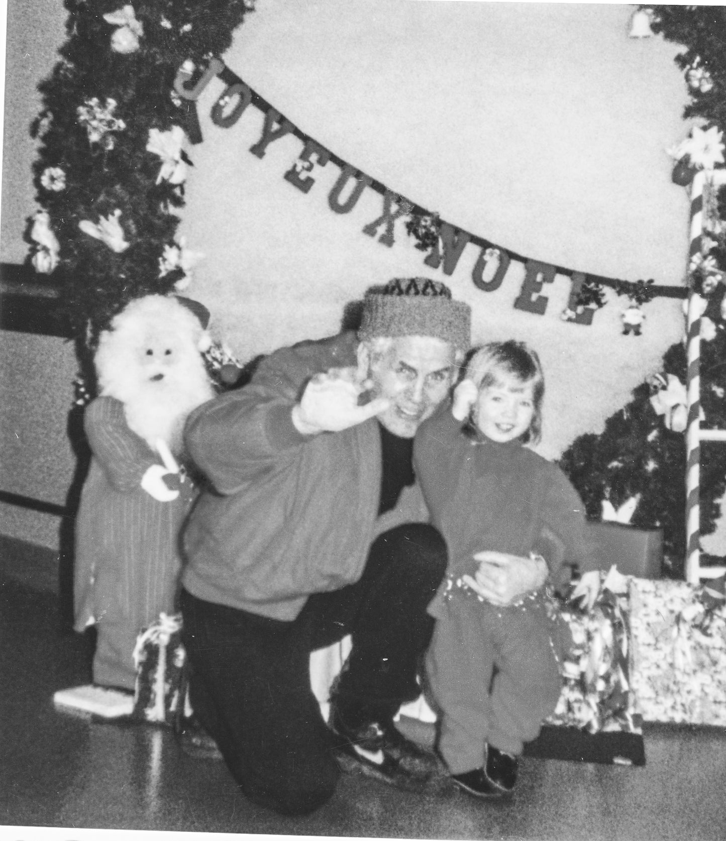 black and white image of Lina's young daughter waving to the camera with Lina's father at Christmas