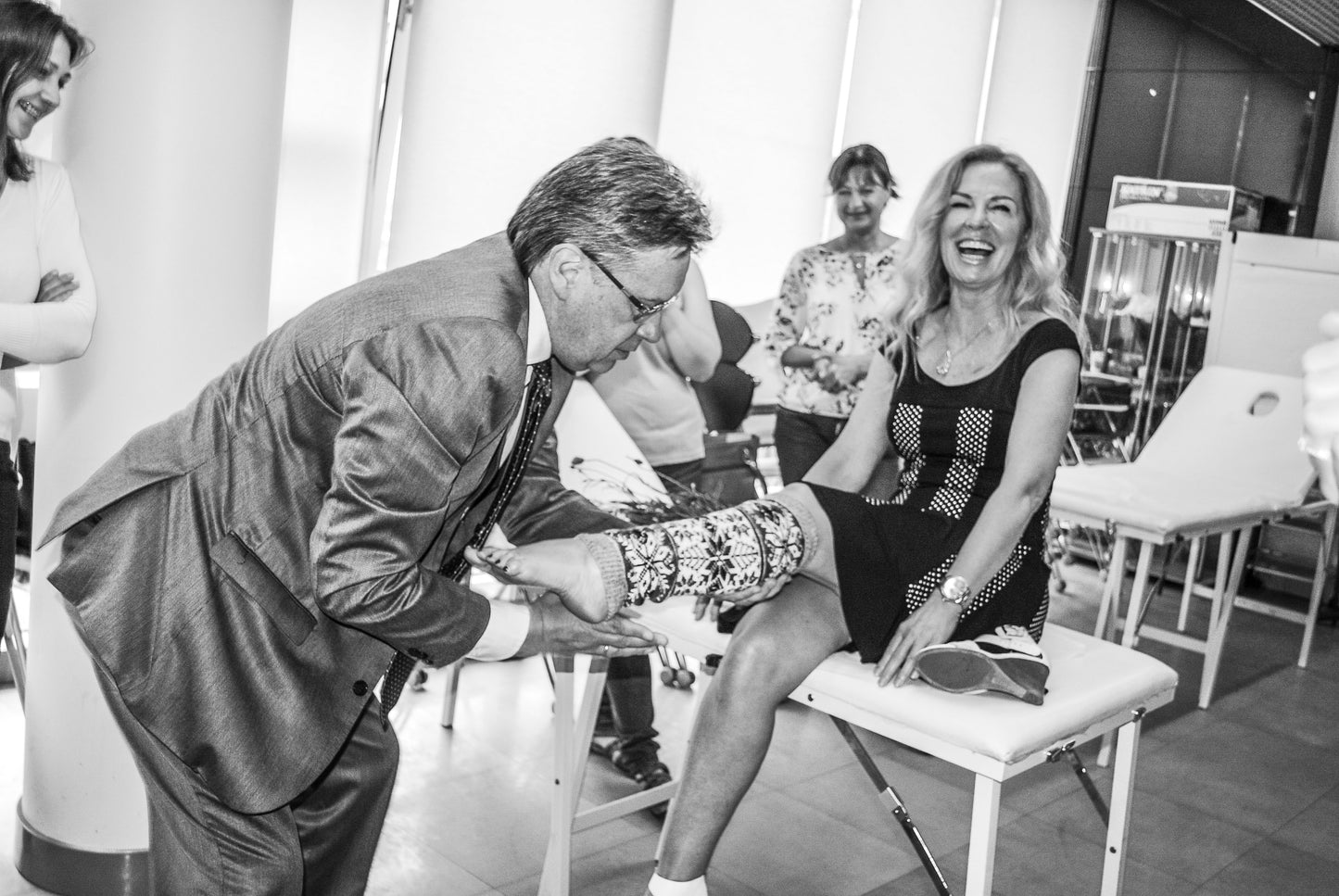 black and white image of Lina having a knit leg warmer put on by one of her Alexandria Professional distributors at a distributor conference in Switzerland