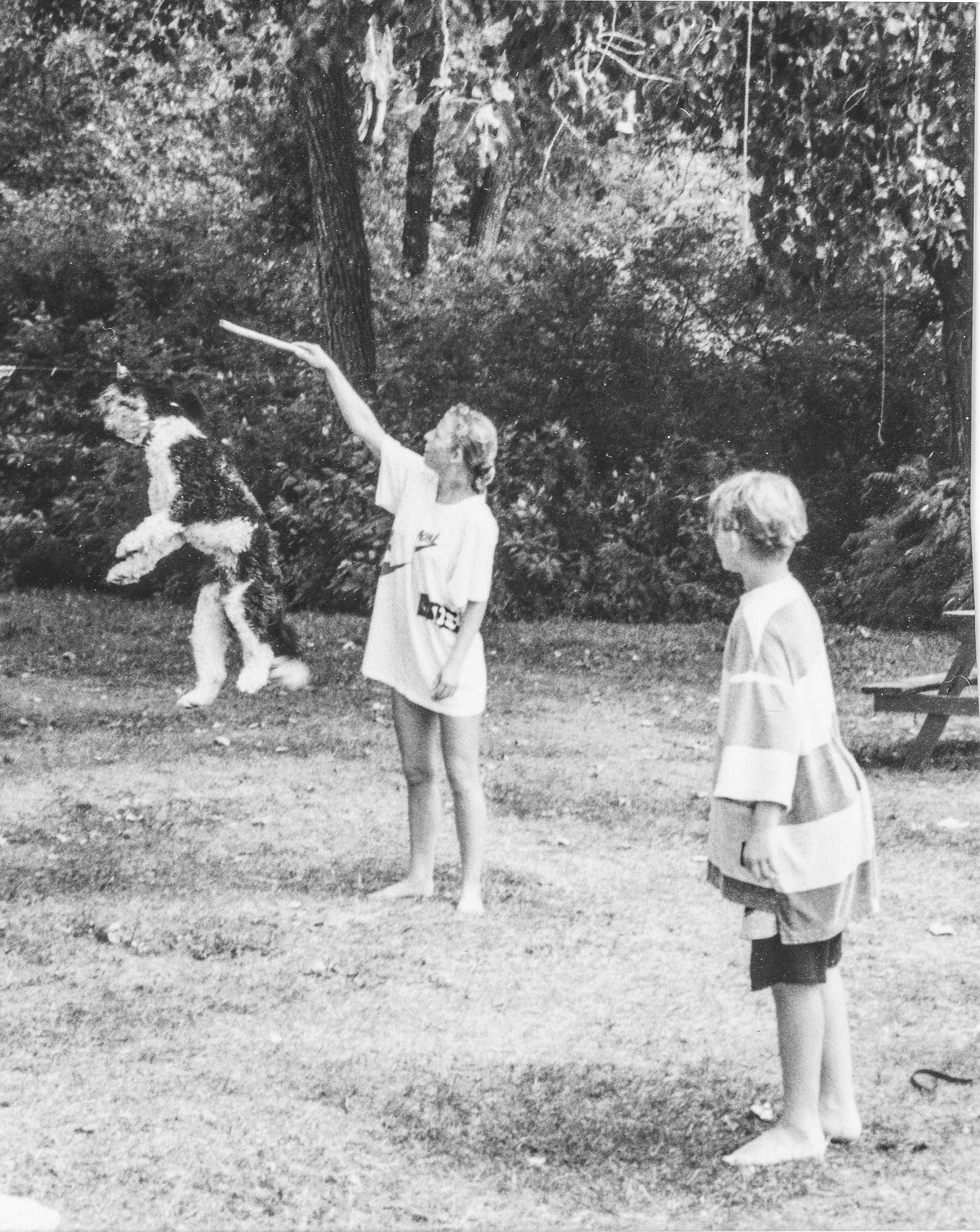 black and white image of Lina and her son outdoors playing with their dog