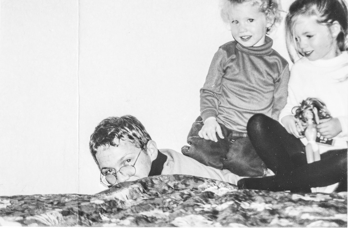 black and white image of Lina's two young  daughters sitting on the back of their older brother