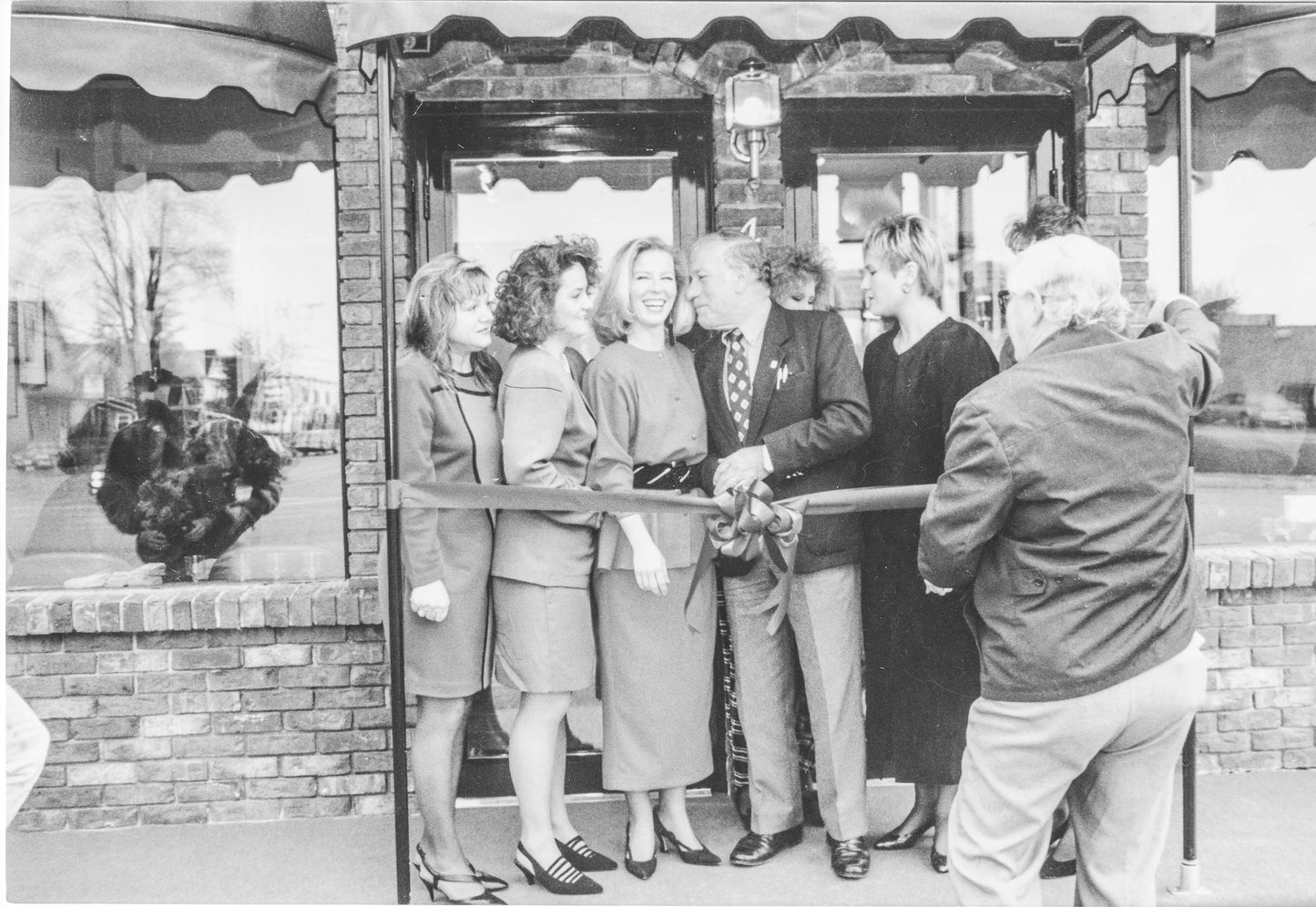 black and white image of Lina and employees in front of her first salon for the ribbon cutting