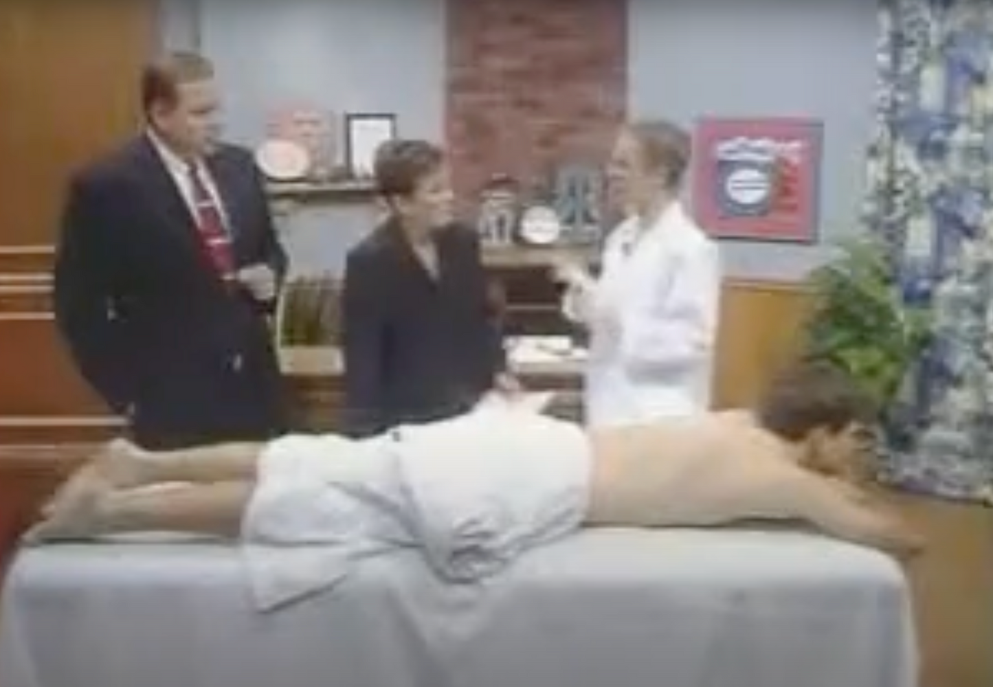 screenshot of Lina in a white lab coat and a man on a massage table from an old TV show she was on in the early 2000s